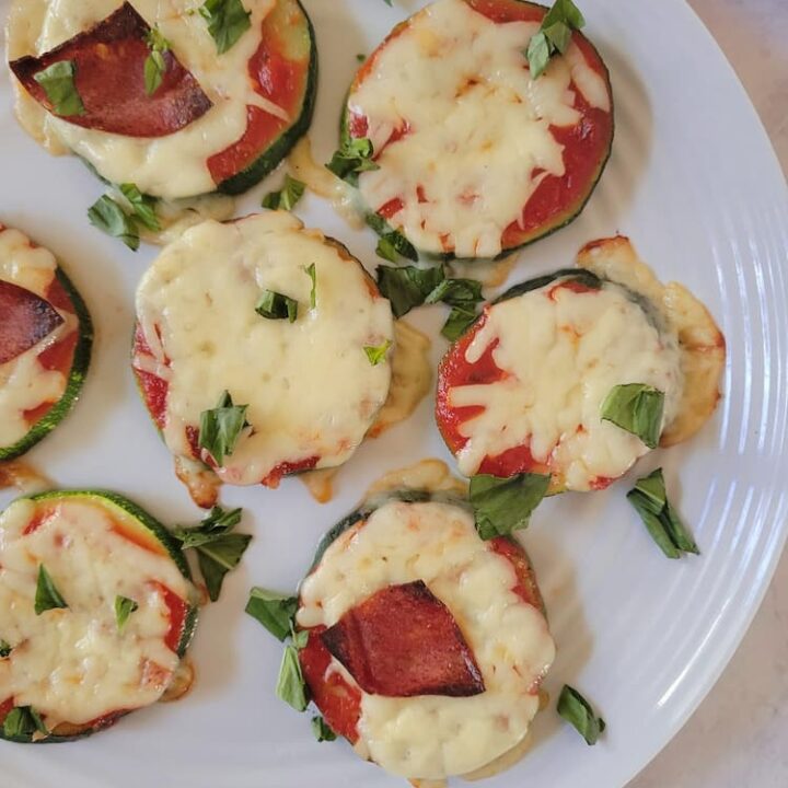 plate with zucchini pizza bites with mozzarella cheese, fresh basil and pepperoni
