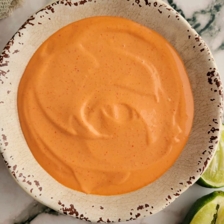 bowl of orange sauce with two halved limes on the side