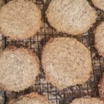 a dozen of freshly baked almond pulp cookies sitting on a black wire rack