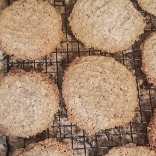 a dozen of freshly baked almond pulp cookies sitting on a black wire rack
