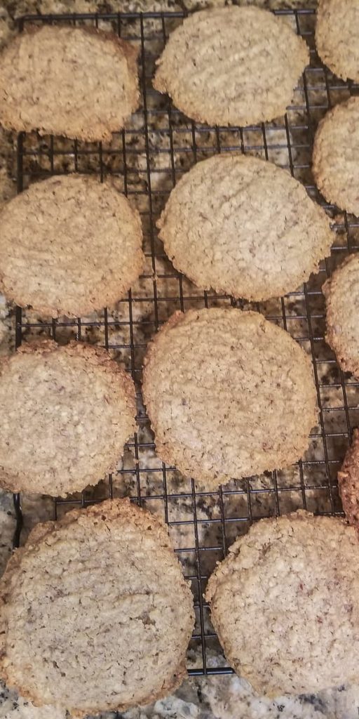 a dozen of freshly baked almond pulp cookies sitting on a black wire rack