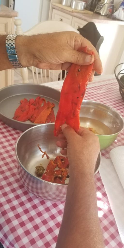 hand holding up a roasted red pepper as it's separating the insides and seeds