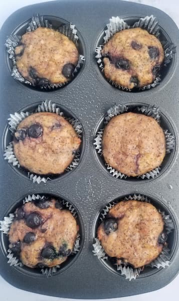 muffin tin with 6 freshly baked blueberry lemon poppy seed muffins