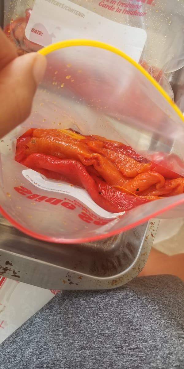 hand pulling open a ziploc bag showcasing some freshly roasted pepper pieces