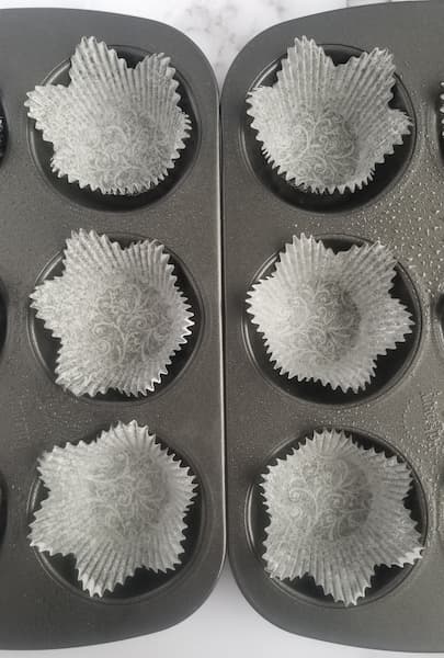 Muffin tray, lined with paper muffin liners, sprayed with cooking spray, 6 visible