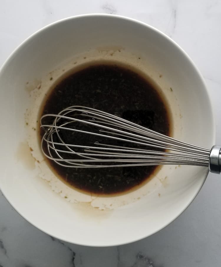 bowl of black sauce with a whisk in it