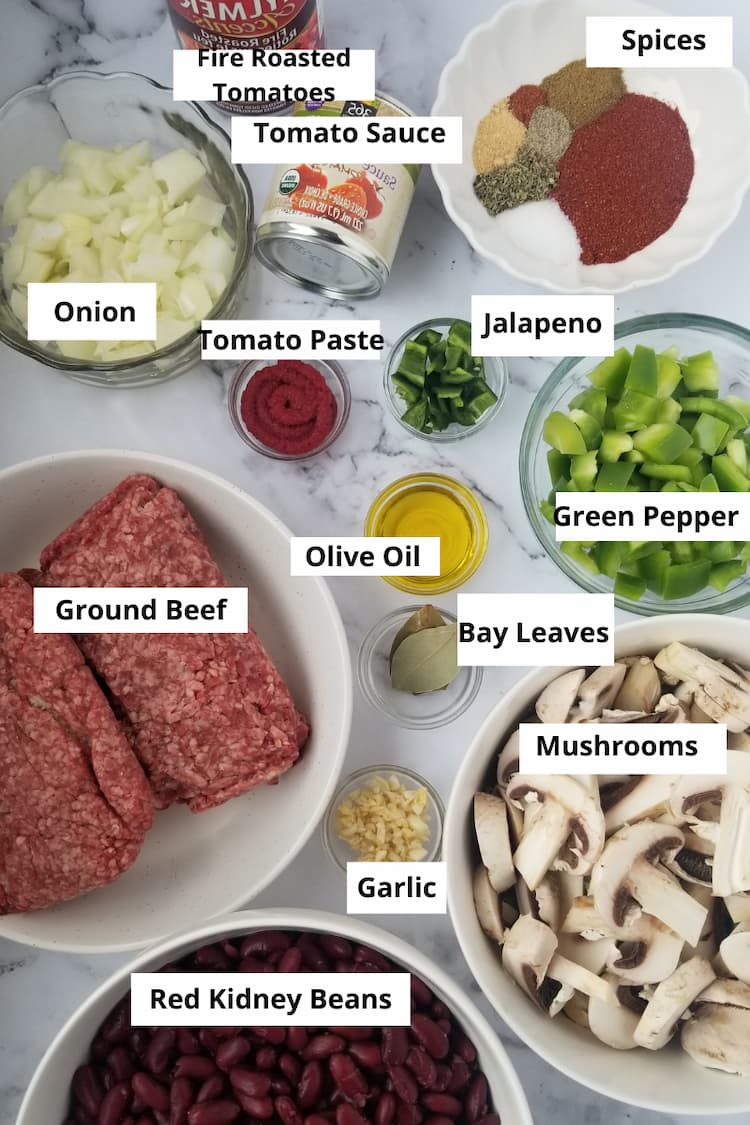 Ingredients to make the best chili - ground beef, red kidney beans, garlic, onions, green pepper, jalapeno, bay leaves, olive oil, tomato paste, tomato sauce, fire roasted tomatoes and an array of spices