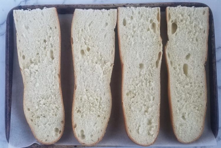 four plain loaves of bread on a parchment lined baking sheet