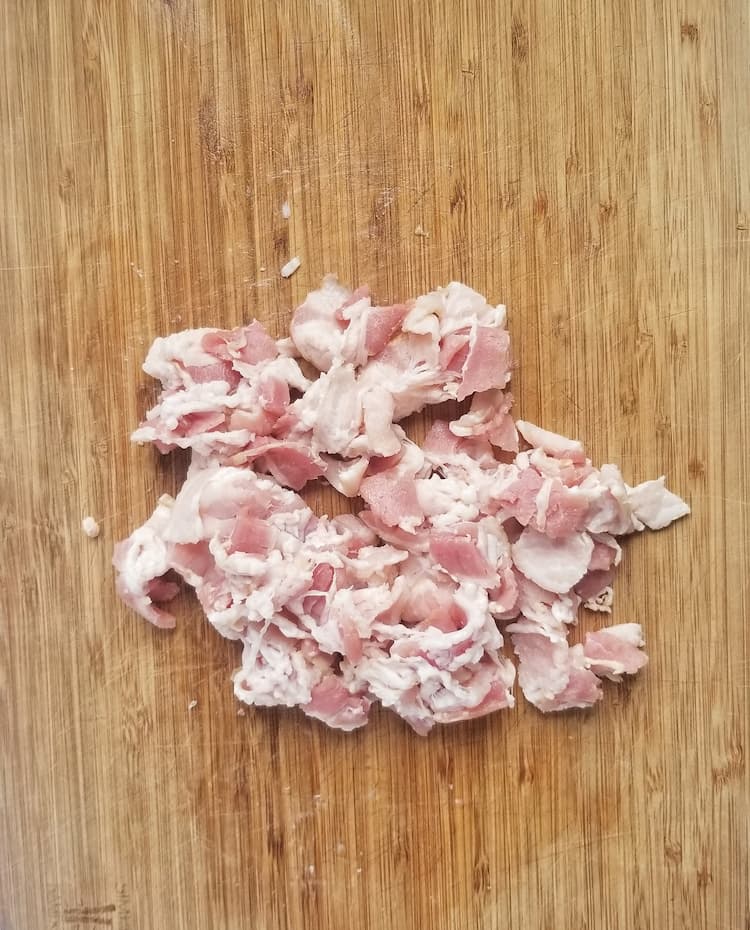 cutting board with raw chopped bacon pieces