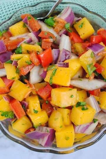 chunks of mango, red onion, parsley, red pepper and habaneros in a small glass bowl