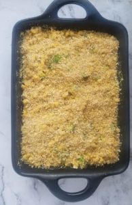 black cast iron casserole with vegan mac and cheese with broccoli topped with breadcrumbs