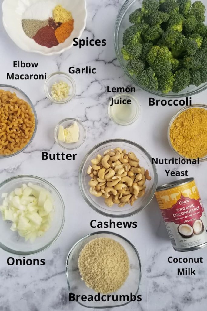ingredients for vegan mac and cheese baked - spices, broccoli, lemon juice, coconut milk, garlic, onions, nutritional yeast, elbow macaroni, cashews, breadcrumbs, butter