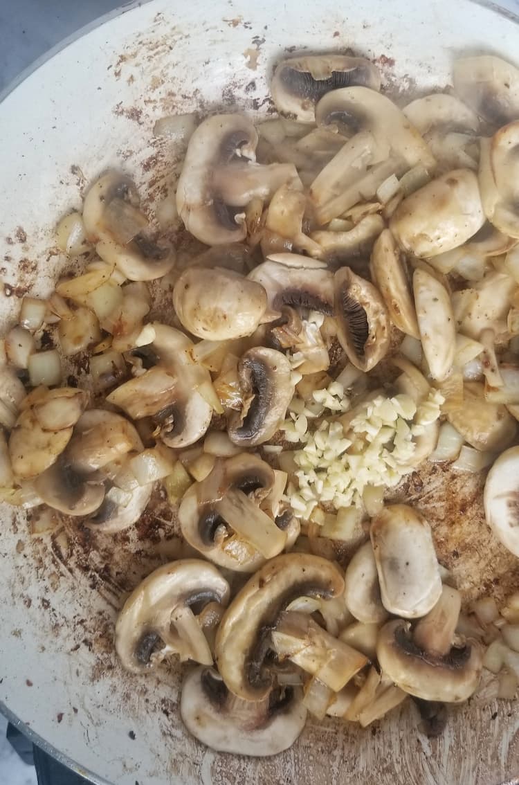 skillet with sliced mushrooms, minced garlic and diced onions