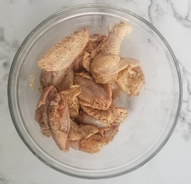 bowl of raw chicken wings seasoned with salt, pepper, garlic powder and baking powder