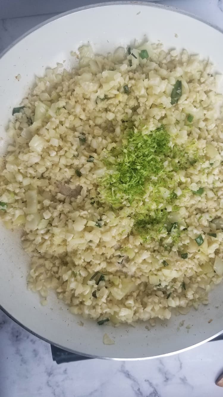 skillet with riced cauliflower, lime zest and chopped cilantro