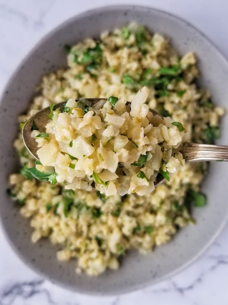 bowl of cauliflower rice cilantro lime, spoon holding up a bit in front of the camera