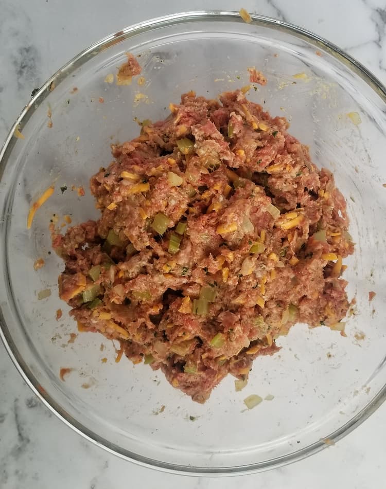 bowl of ground meat mixed with other ingredients such as grated cheddar cheese and celery