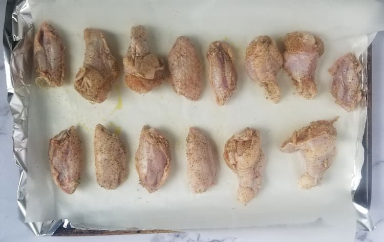 parchment lined baking sheet with raw chicken wings in a single layer