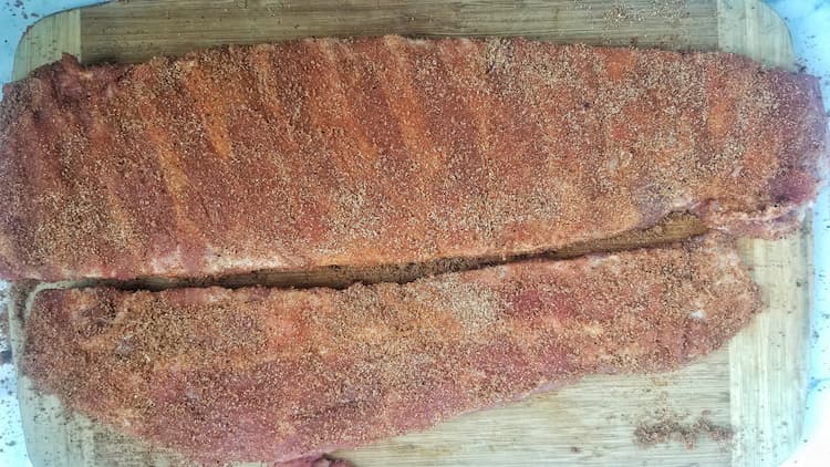 two seasoned racks of ribs on a cutting board