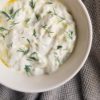 bowl of homemade tzatziki sauce with fresh dill and olive oil on top