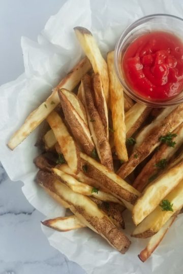 bowl of air fryer fries with ketchup and chopped parsley