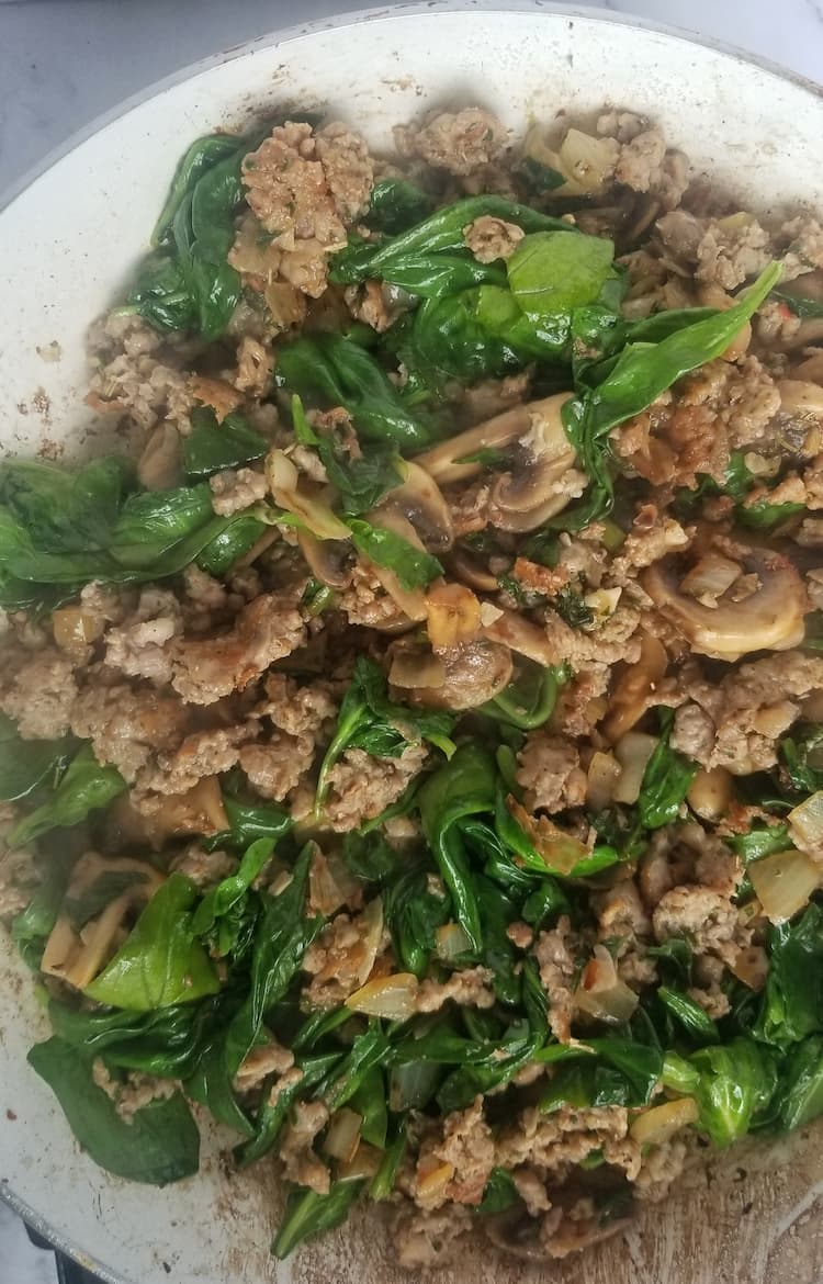 skillet with spinach, mushrooms, browned ground meat