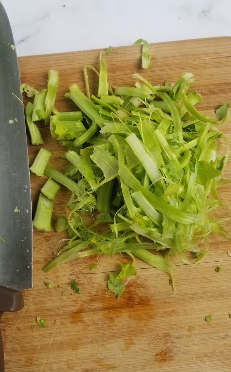 cutting board with a knife and rapini stem shavings