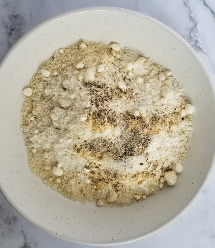 a white bowl of flour, spices and parmesan cheese