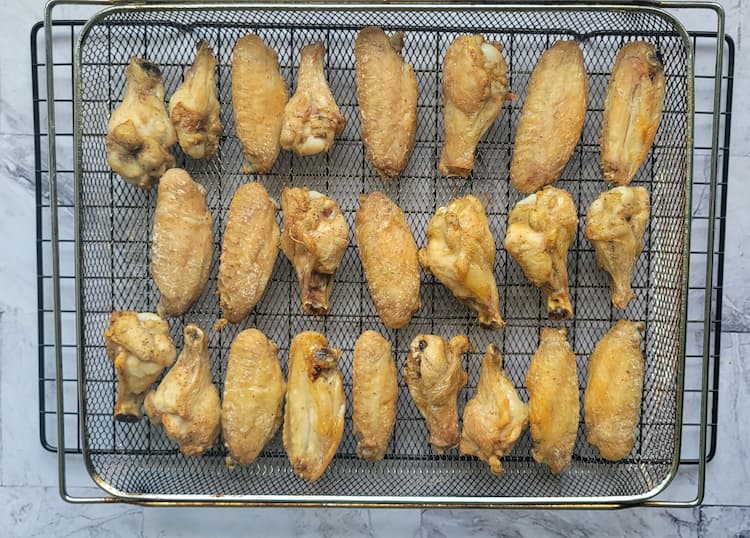 3 rows of cooked seasoned chicken wings in an air fryer basket