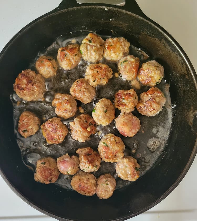 skillet with oil and bowned mini meatballs