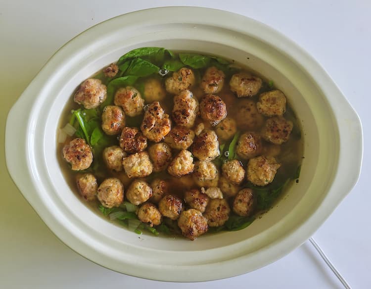 crock pot with mini meatballs, broth and spinach