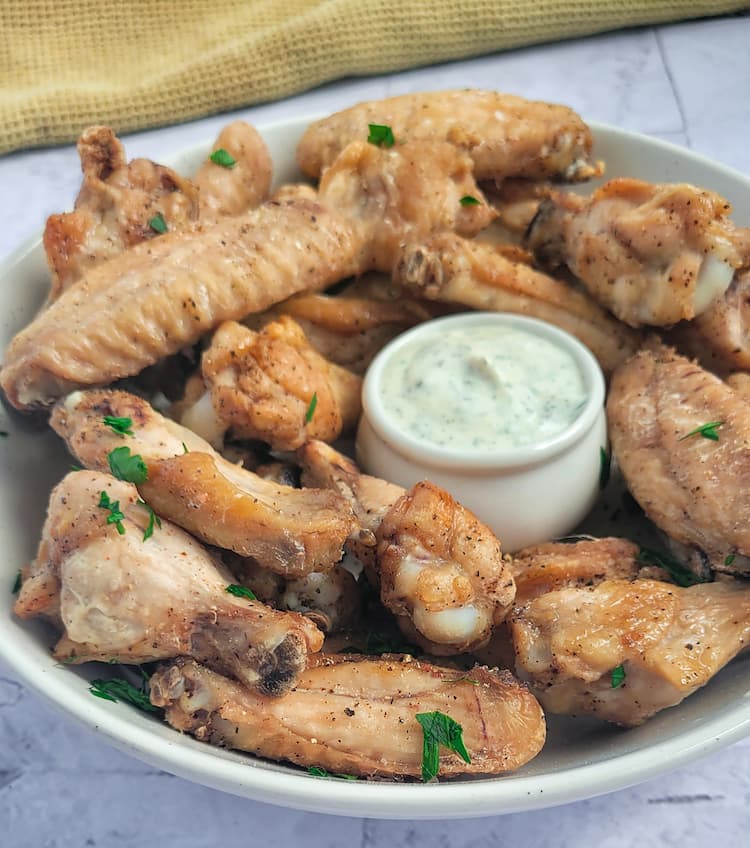 air fried chicken wings in a bowl with ranch dipping sauce, garnished with fresh chopped parsley