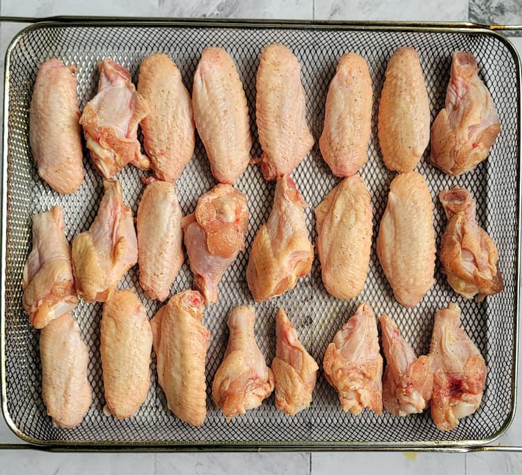 3 rows of raw seasoned chicken wings in an air fryer basket