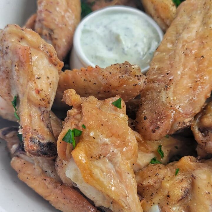 air fried chicken wings in a bowl with ranch dipping sauce, garnished with fresh chopped parsley