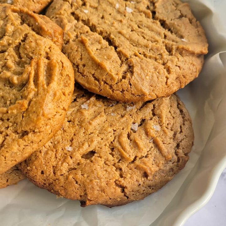 side view of flourless peanut butter cookies on a parchment lined plate