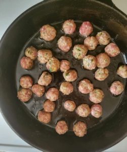 skillet with oil and raw mini meatballs
