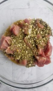 bowl of pork chunks with spices and minced garlic on top