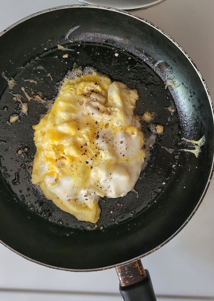 skillet with scrambled eggs, salt and pepper