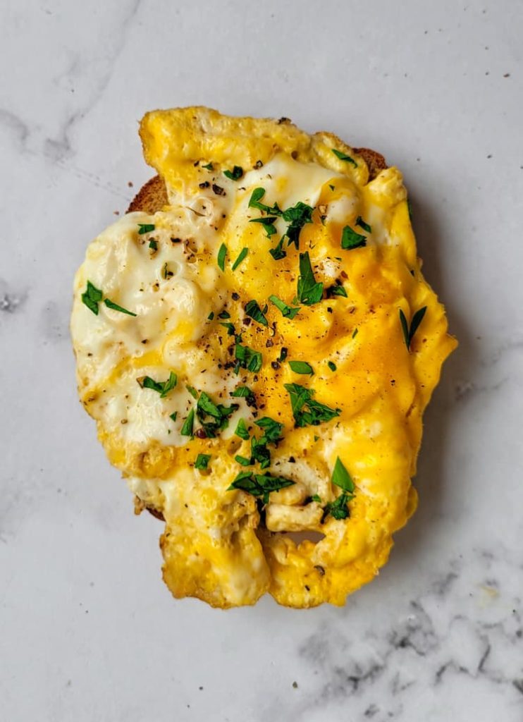 scrambled eggs on toast garnished with fresh chopped parsley