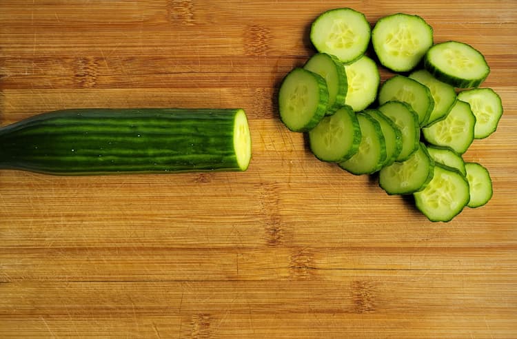 cucumber on a cutting board, half whole and half in slices