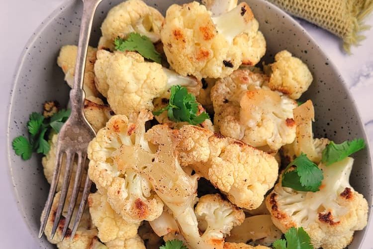 bowl of roasted cauliflower with chopped parsley, fork in the bowl
