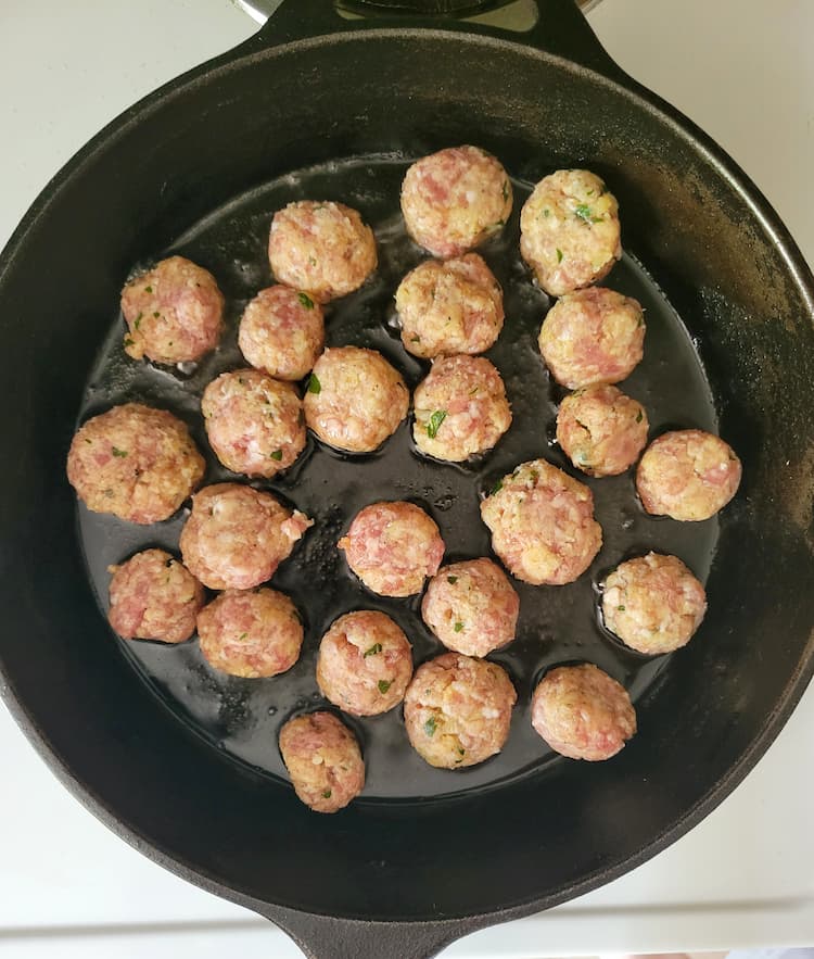 skillet with oil and raw mini meatballs