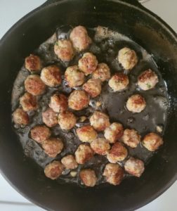 skillet with oil and browned mini meatballs