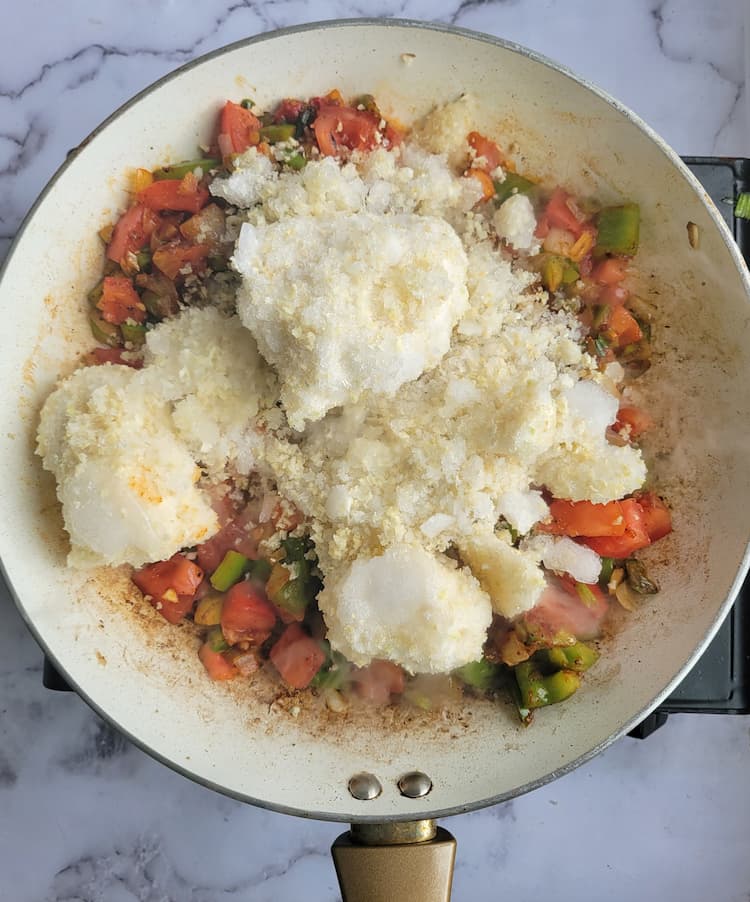 skillet with frozen chunks of riced cauliflower, diced tomatoes, onions and green bell pepper