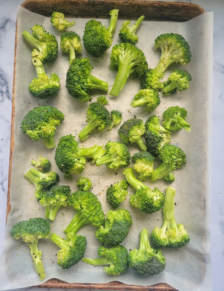 sheet pan with raw broccoli florets seasoned with salt and pepper