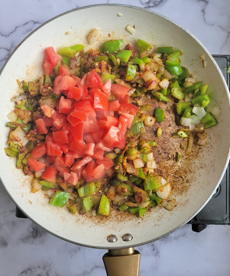skillet with diced tomatoes, green bell peppers, onions