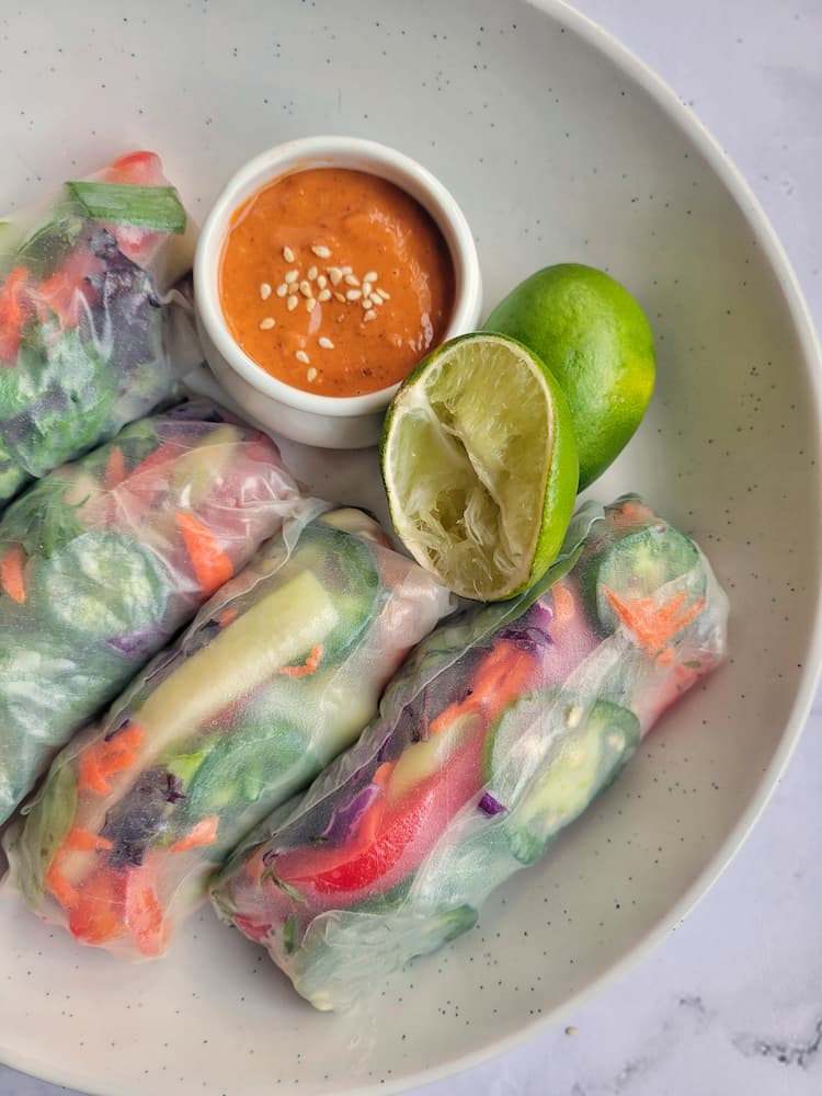 4 fresh veggie spring rolls with peanut sauce and halved limes