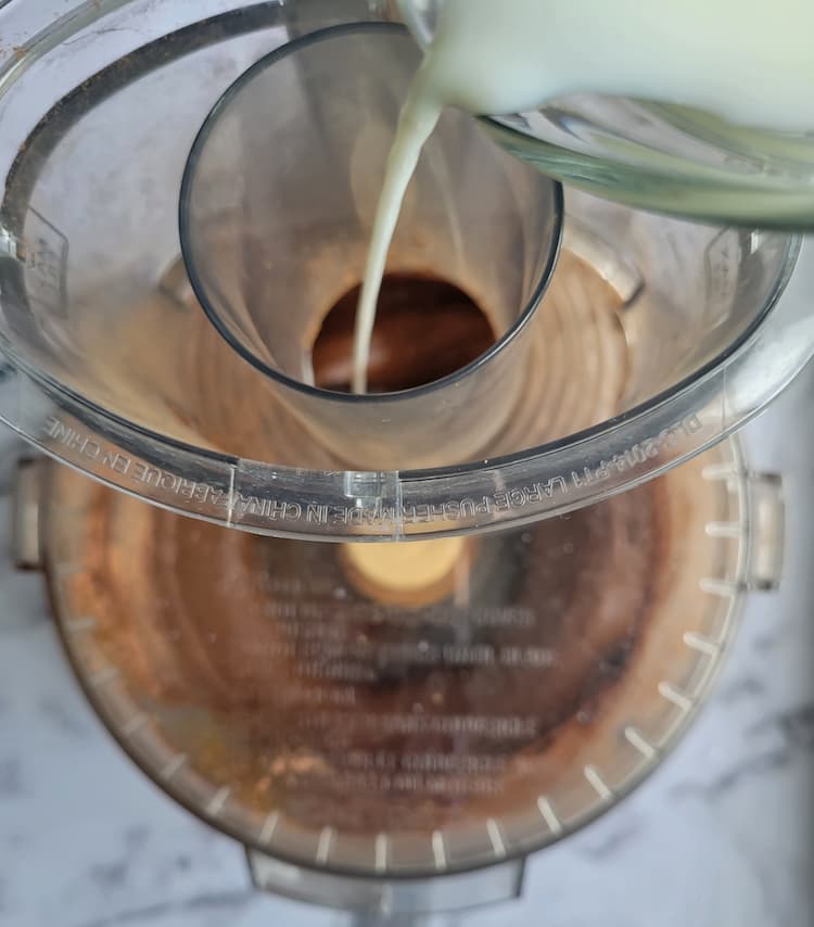 milk pouring into the spout of a food processor