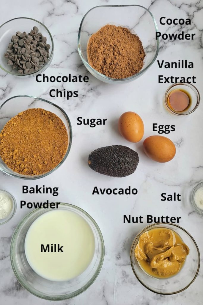 ingredients for avocado brownies - avocado, cocoa powder, vanilla extract, chocolate chips, milk, nut butter, eggs, sugar, salt, baking powder