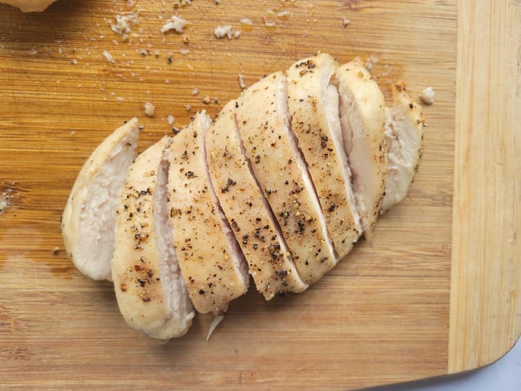 a cooked sliced chicken breast on a cutting board